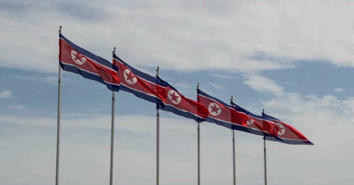 North Korean flags flying on poles against a cloudy sky